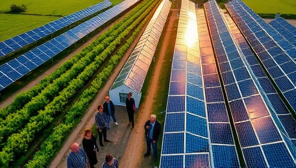 An aerial view of a vibrant community solar farm with rows of solar panels glistening under the sun, surrounded by green fields and a diverse group of people happily engaged in a solar energy workshop, showcasing community involvement and sustainability.