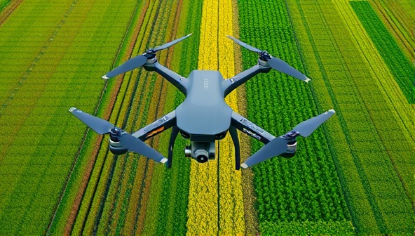 An aerial view captured by a drone showing lush green fields with colorful crop patterns, highlighting the perspective and data insights that drones can provide to farmers for precision agriculture.