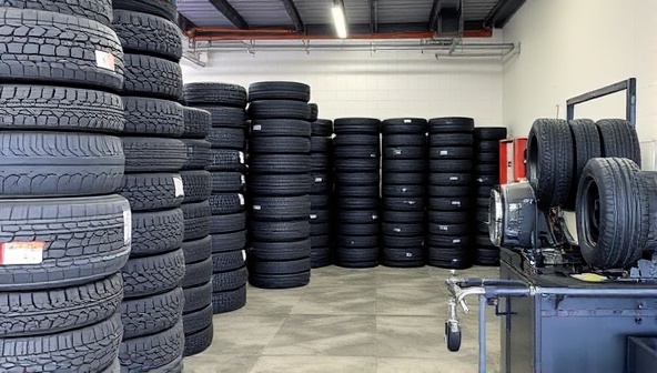 An organized storage area filled with neatly stacked tires of different sizes and types, a tire changing station with professional equipment, and a waiting area for customers, showcasing the efficiency and convenience of the tire swap and storage service.
