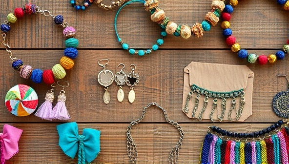 An artistic flat lay of upcycled fashion accessories arranged on a wooden table, featuring colorful fabric scraps, beads, and metallic accents, conveying the creativity and eco-friendliness of the brand.