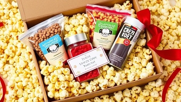An elegant subscription box filled with colorful and gourmet popcorn varieties, nestled in a bed of decorative popcorn kernels, accompanied by a small note card and a festive ribbon, creating a sense of anticipation and indulgence.