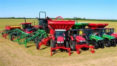 An array of well-maintained agricultural machinery lined up in a rural setting with a diverse range of equipment, from plows to seeders, under a clear blue sky, showcasing the convenience and variety of farm equipment rentals available through the platform.