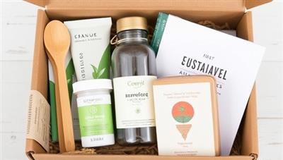 A collection of sustainable travel products neatly arranged in a box, including bamboo utensils, organic skincare samples, a reusable water bottle, and a travel journal, promoting eco-friendly and mindful travel practices.