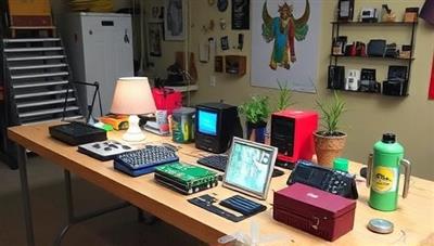 A workshop table filled with colorful upcycled tech creations, such as lamps made from old circuit boards, planters from computer parts, and wall art from discarded gadgets, showcasing the creativity and sustainability of TechReNew Studio.