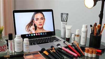 A virtual beauty consultation setup with a laptop displaying a makeup tutorial, skincare products, and a variety of makeup brushes and tools, creating a virtual beauty studio atmosphere.