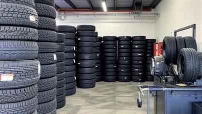An organized storage area filled with neatly stacked tires of different sizes and types, a tire changing station with professional equipment, and a waiting area for customers, showcasing the efficiency and convenience of the tire swap and storage service.