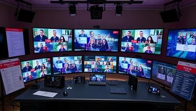 A virtual event control room setup with multiple screens displaying live event feeds, surrounded by event planning checklists, mood boards, and a vibrant event branding concept, symbolizing the behind-the-scenes coordination and creativity of virtual event planning services.