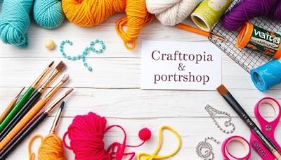 An artistic flat lay of a craft workshop table with colorful yarn, paintbrushes, beads, and a completed DIY project, conveying the creativity and hands-on experience provided by Craftopia Creations' subscription boxes.