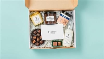 An artistic flat lay of various gift items like candles, chocolates, skincare products, and a personalized note card arranged in a visually appealing gift box, showcasing the elegance and customization of the service.