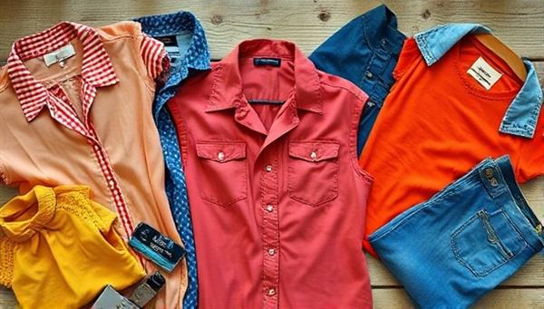 An aesthetically pleasing flat lay of colorful vintage clothing items arranged on a rustic wooden table, with natural lighting highlighting the unique textures and patterns, conveying a sense of style and sustainability.