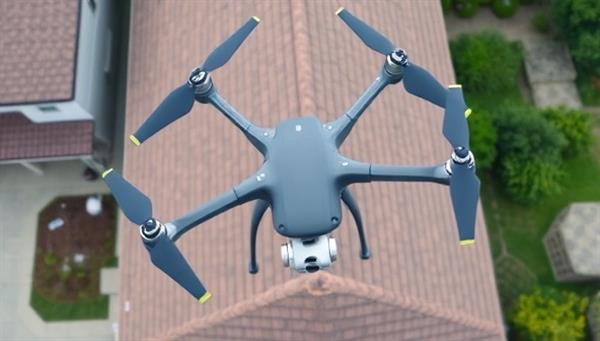 An aerial view captured by a drone showing a detailed inspection of a residential roof, highlighting the precision and efficiency of drone-assisted roof assessment services in identifying potential issues and ensuring property maintenance.